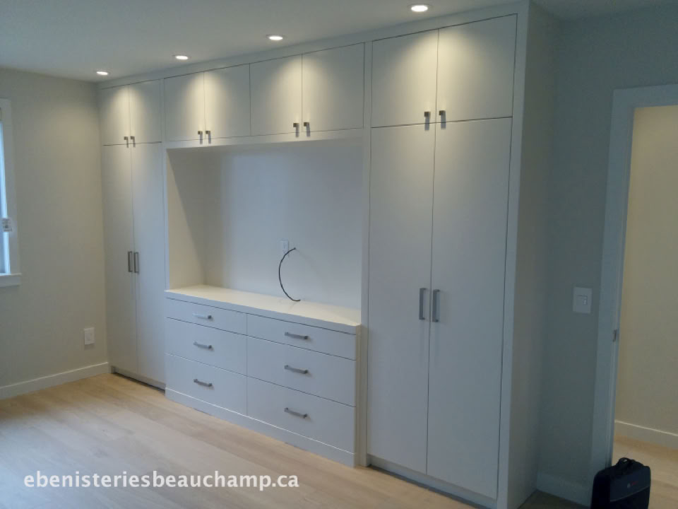 Built-in white cabinetry with upper and lower cabinets, drawers in the center, and recessed lighting above.