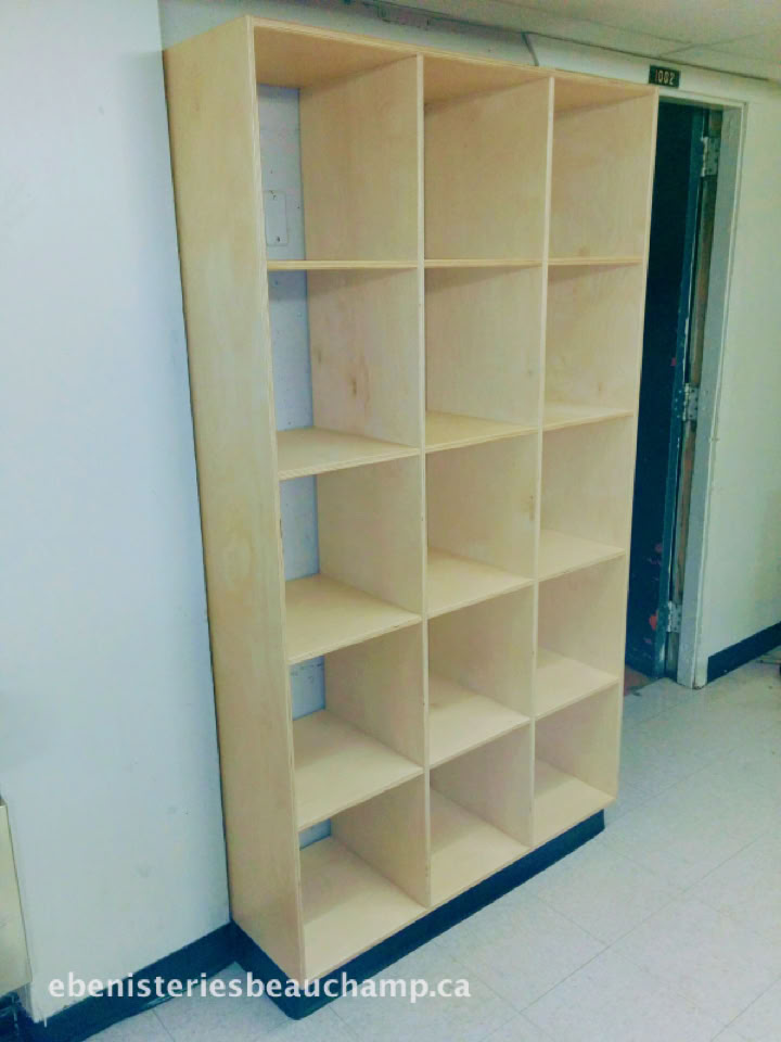 Étagère en bois avec quinze compartiments, placée contre un mur blanc.