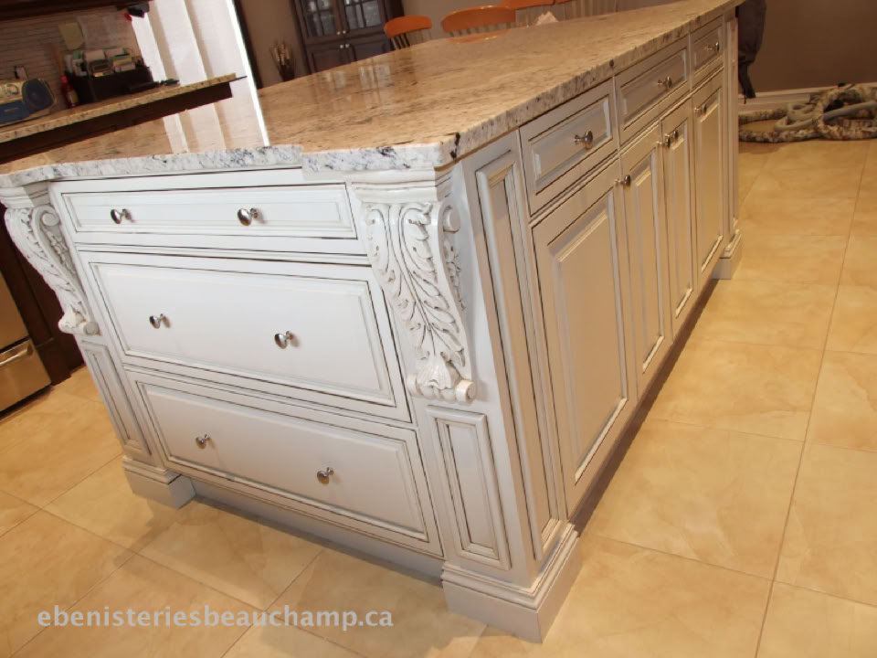A kitchen island with ornate white cabinetry and a granite countertop on a tiled floor.