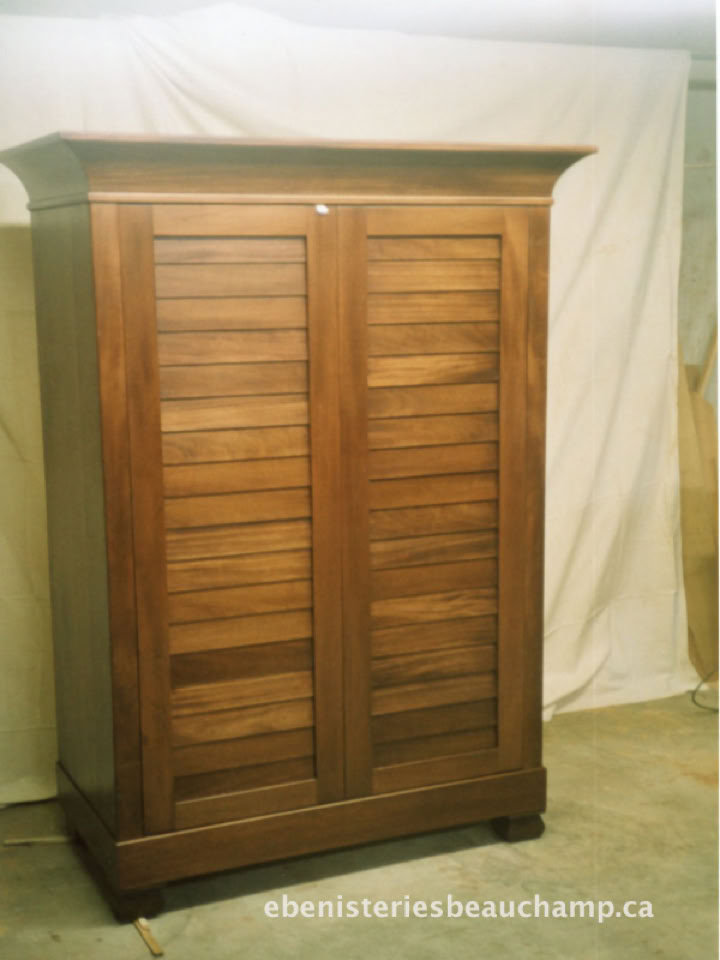 Armoire en bois avec deux portes à lattes, posée devant un fond blanc.