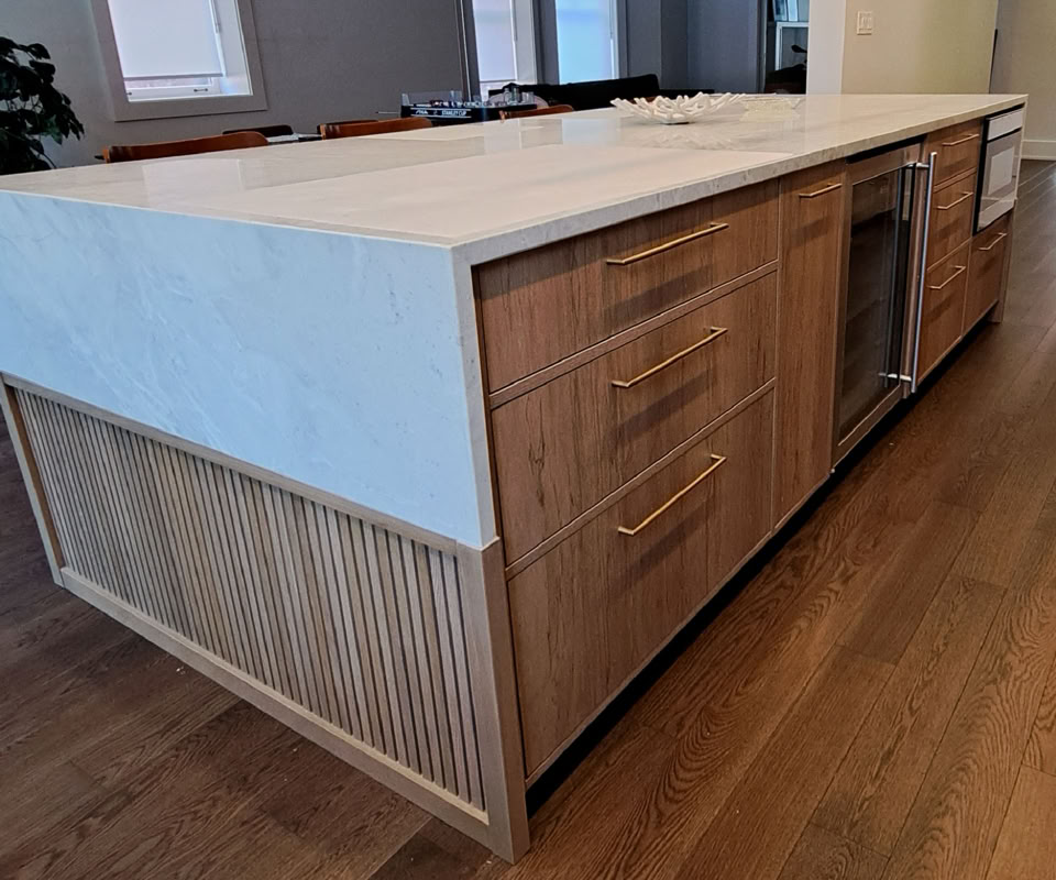 A kitchen island with a white countertop, wooden drawers, and cabinets, set on a wooden floor.